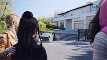 a woman in a pink hoodie stands in front of a large white building that says ' ffrs ' on it