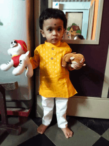 a little boy holding a stuffed animal in front of a refrigerator