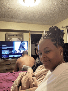 a woman sits in front of a tv that says netflix on the screen