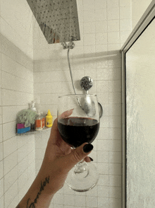 a woman holds a glass of wine in front of a shower head