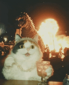 a cat with a pearl necklace is holding a glass in front of a fire