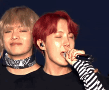 a man with red hair singing into a microphone next to another man with blonde hair