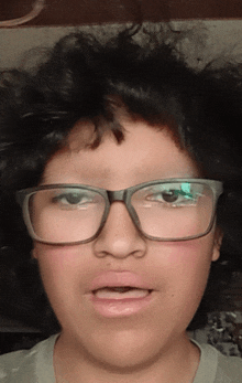 a young boy wearing glasses makes a funny face with his mouth open