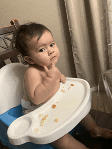 a baby is sitting in a high chair and making a funny face