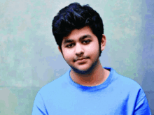 a young man is wearing a blue shirt and looking at the camera