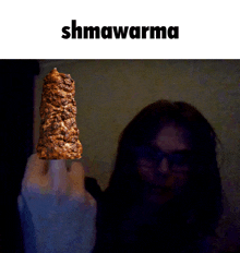 a picture of a person holding a piece of food that says shmawarma