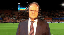 a man in a suit and tie is standing in front of a stadium with a sign that says pnc in the background