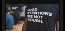 a person wearing a black shirt that says good intentions are not enough