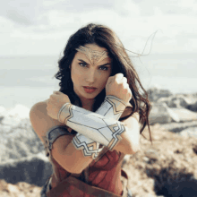 a woman in a wonder woman costume stands on a rocky hillside