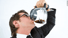 a man in a suit is drinking from a coffee maker