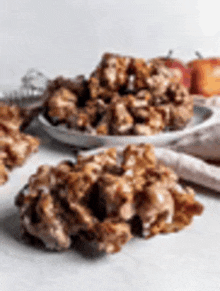 a close up of a plate of apple fritters on a table with apples in the background .