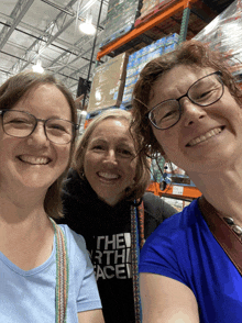 three women are posing for a picture and one of them is wearing a north face sweatshirt