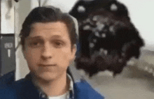 a man in a blue jacket is taking a selfie in front of a monster .