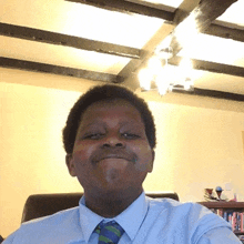 a young man wearing a blue shirt and green tie looks at the camera