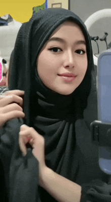 a woman in a black hijab is taking a selfie