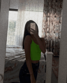 a woman in a neon green crop top taking a selfie in front of a mirror