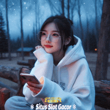 a girl wearing glasses and a white hoodie is holding a cell phone with situs slot gacor written on the bottom