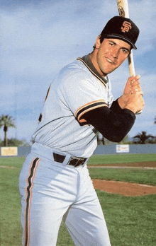 a man in a san francisco giants uniform is holding a baseball bat on a baseball field .