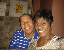 a man and a woman are posing for a picture in front of a sign that says riesgo electrico