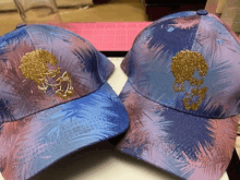 two baseball caps with palm trees on them on a table