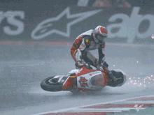 a man is riding a red and white motorcycle on a wet track with the letters tcs on the front