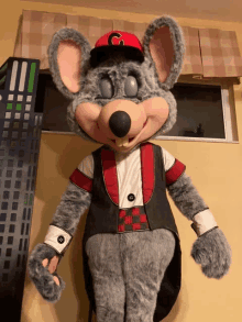 chuck e cheese mascot wearing a red c hat