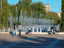 a group of people standing in front of a fountain with a building in the background that says ' occr '