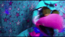 a stuffed animal is laying on a bed with a blue blanket with stars on it