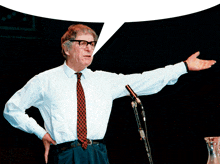 a man wearing glasses and a tie stands in front of a microphone with a speech bubble above his head