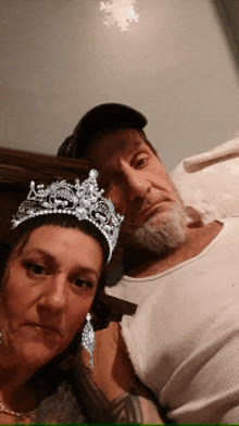 a man and a woman are posing for a picture and the woman is wearing a crown