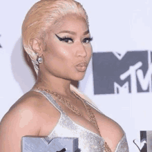 a woman in a silver dress is standing in front of a mtv logo .