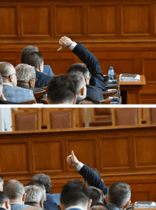 a man in a suit raises his hand to answer a question in a parliament