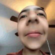 a close up of a person 's face with a ceiling fan behind them .