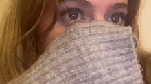 a close up of a woman covering her face with a sweater