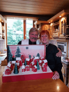 a man and a woman standing next to a box that says ' christmas ' on it