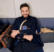 a man sitting on a couch next to a laptop and a purse