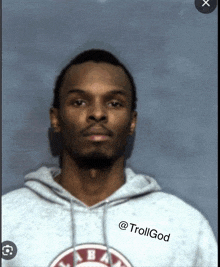 a man wearing an alabama sweatshirt stands in front of a blue backdrop