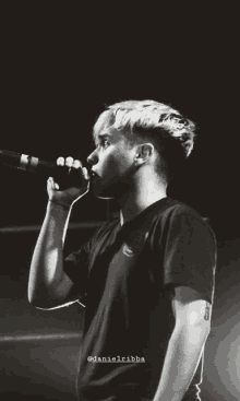 a black and white photo of a man singing into a microphone with the name danielribba on the bottom right