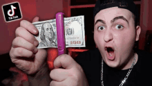 a man is holding a 100 dollar bill and a purple object