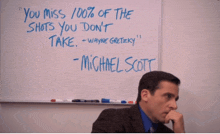 a man sitting in front of a white board with a quote from michael scott