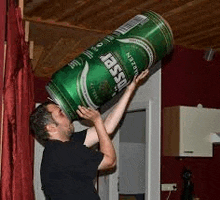 a man is holding a large green can of beer over his head .