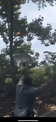 a man is throwing a basketball at a basketball hoop while wearing a gray shirt with the letter w on the sleeve