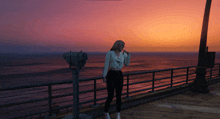 a woman standing on a pier looking at the ocean