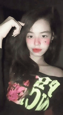 a young girl wearing a black shirt with a pink heart on her face is taking a selfie .