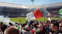 a crowd of people in a stadium with a red white and green flag that says ' amsterdam ' on it