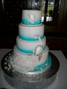 a turquoise and white wedding cake with pearls and flowers