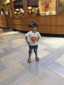 a young boy wearing a superman shirt and a black hat