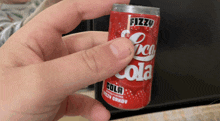 a person is holding a fizzy cola can