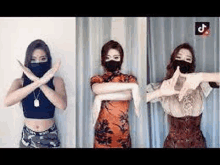 three women wearing face masks are making a cross sign with their arms .