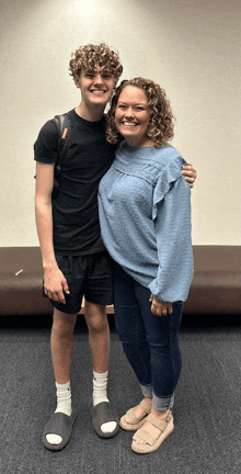 a woman in a blue sweater is standing next to a boy in a black shirt